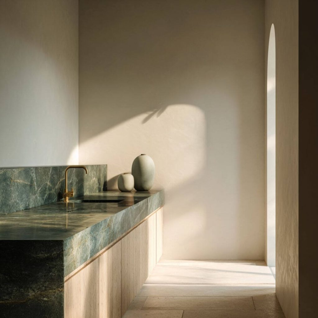 Cocina del Proyecto Mentidero, con encimera de mármol verde y grifería dorada. Interiorismo sobrio y funcional en Cádiz.