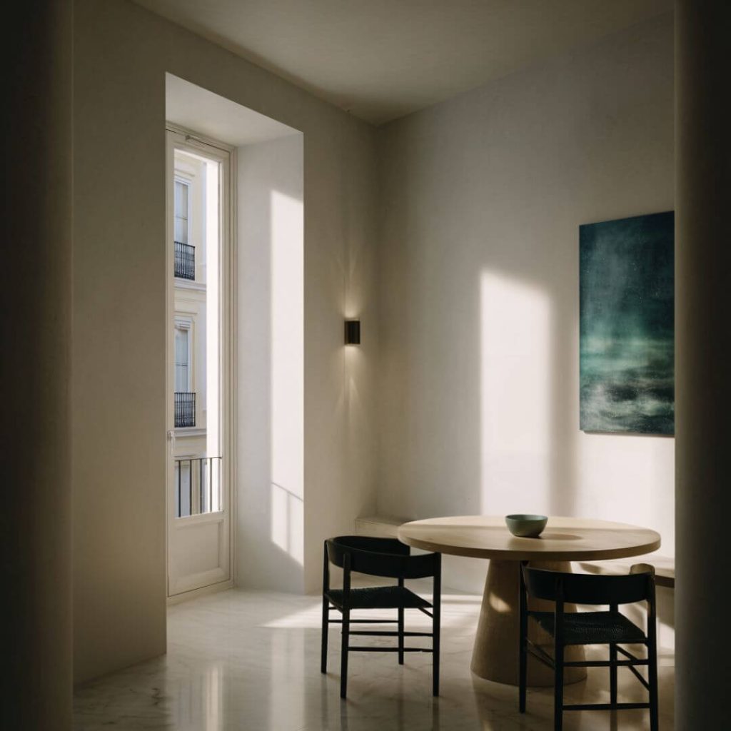 Comedor del Proyecto Mentidero. Mesa redonda de madera, sillas negras y obra abstracta en verde. Interiorismo editorial en Cádiz.