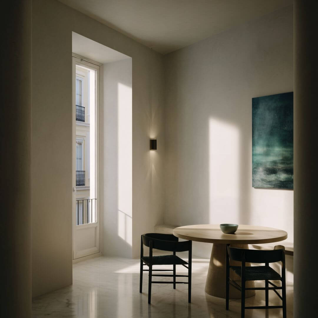 Comedor del Proyecto Mentidero. Mesa redonda de madera, sillas negras y obra abstracta en verde. Interiorismo editorial en Cádiz.