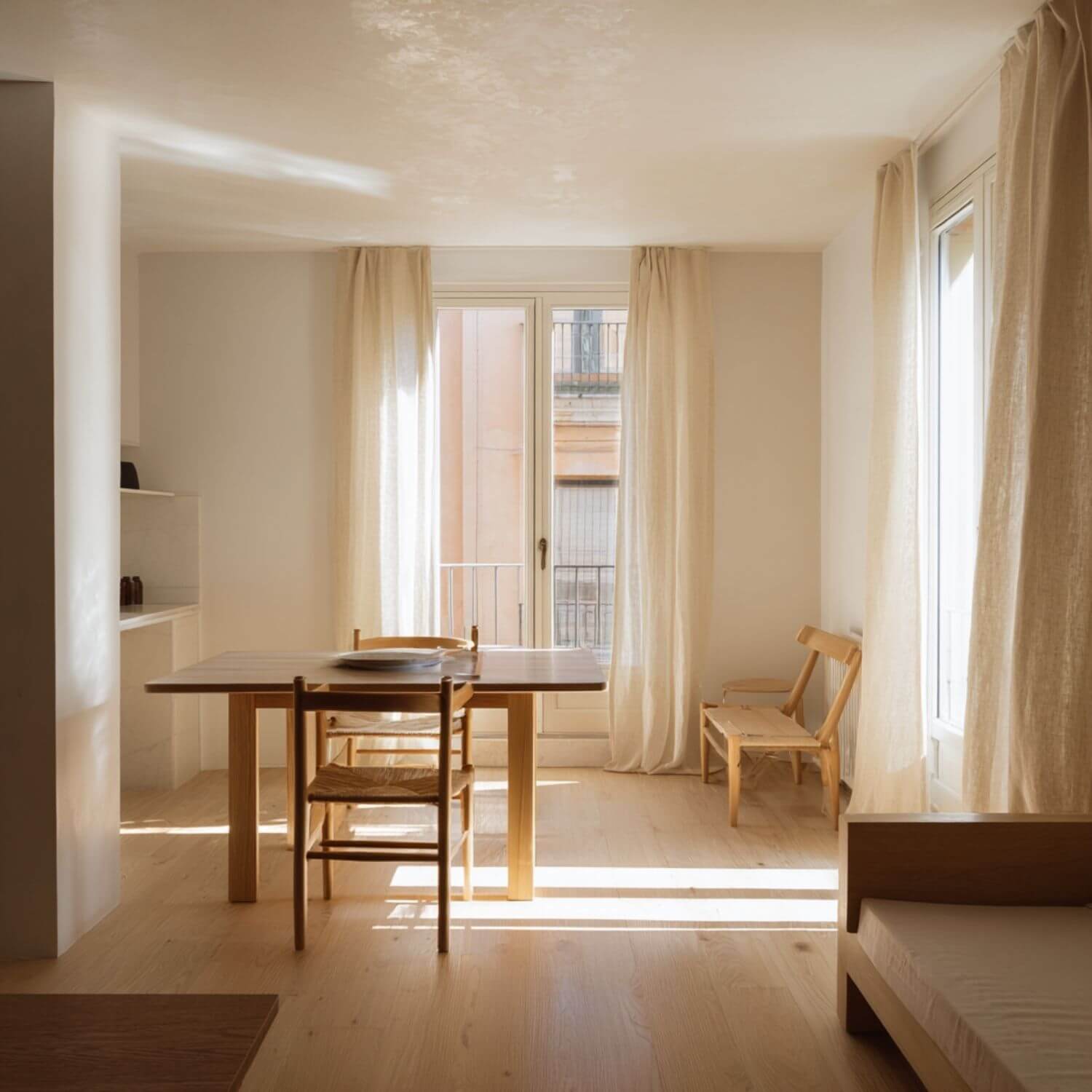 Apartamento luminoso en Sevilla con diseño de interiores minimalista, mesa de madera clara y cortinas de lino.