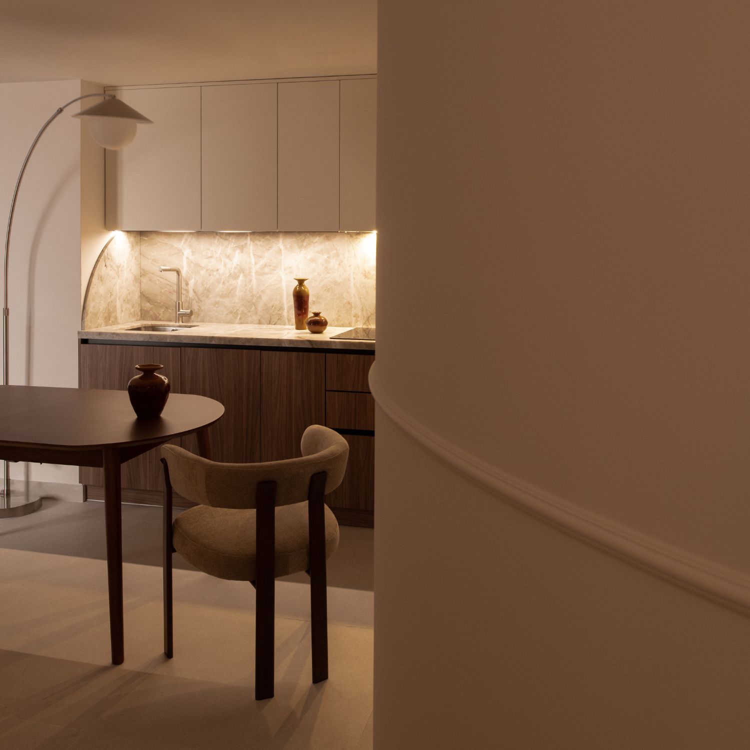 Cocina integrada vista desde la curva arquitectónica del pasillo en un piso reformado en la Encarnación, Sevilla.