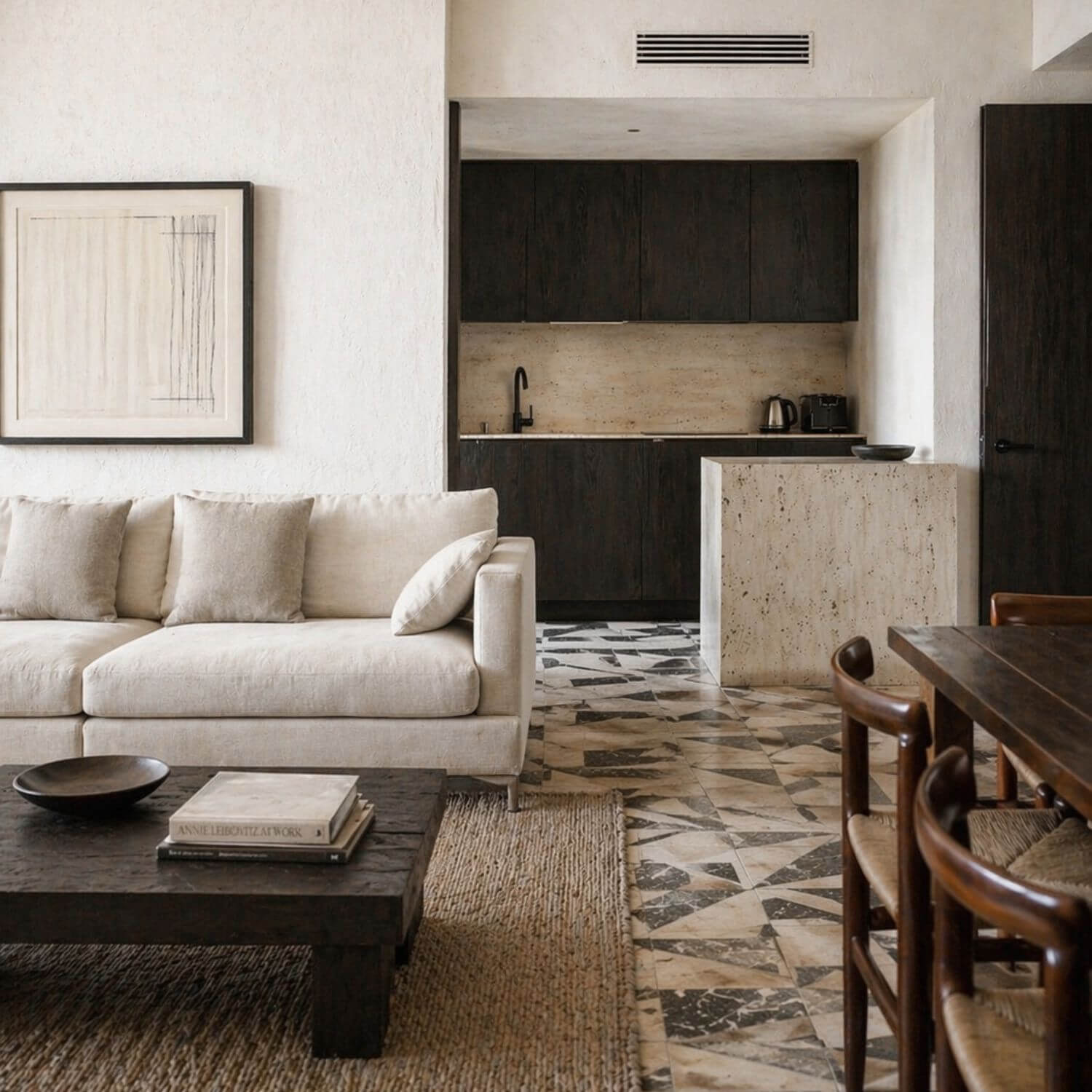 Salón y cocina del Proyecto de interiorismo en Sevilla con mobiliario en madera oscura, piedra natural y pavimento geométrico. Proyecto Vigía.