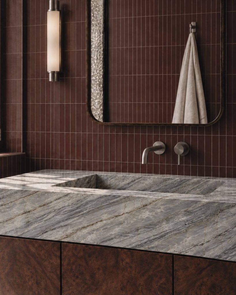 baño de interiorismo en sevilla con lavabo de piedra azul, azulejo borgoña y acero cepillado