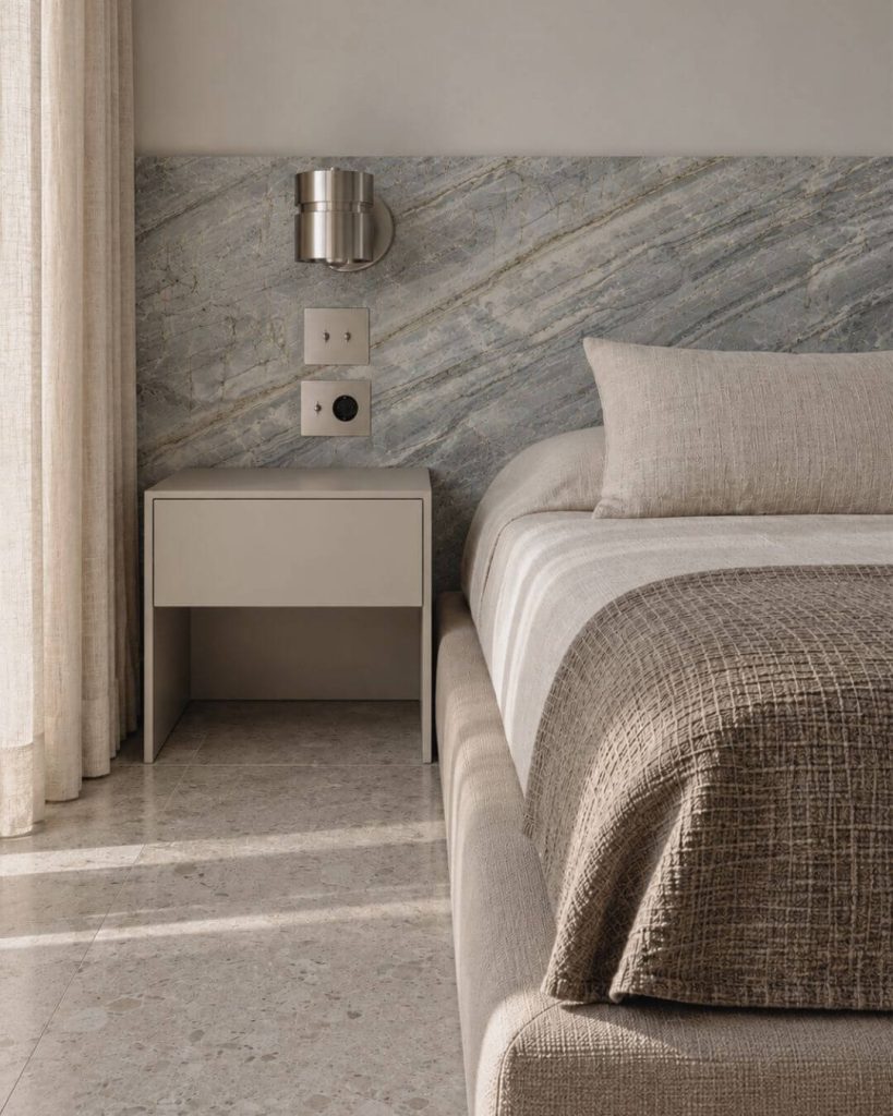 dormitorio de interiorismo en sevilla con cabecero de piedra azul y textiles neutros
