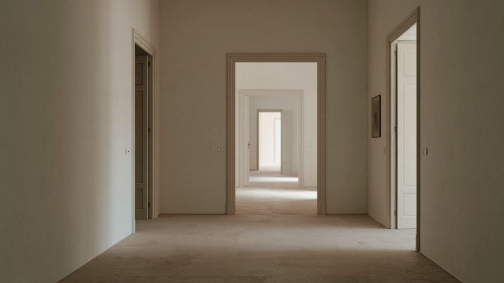 Pasillo con varias puertas abiertas y luz natural al fondo de la vivienda.