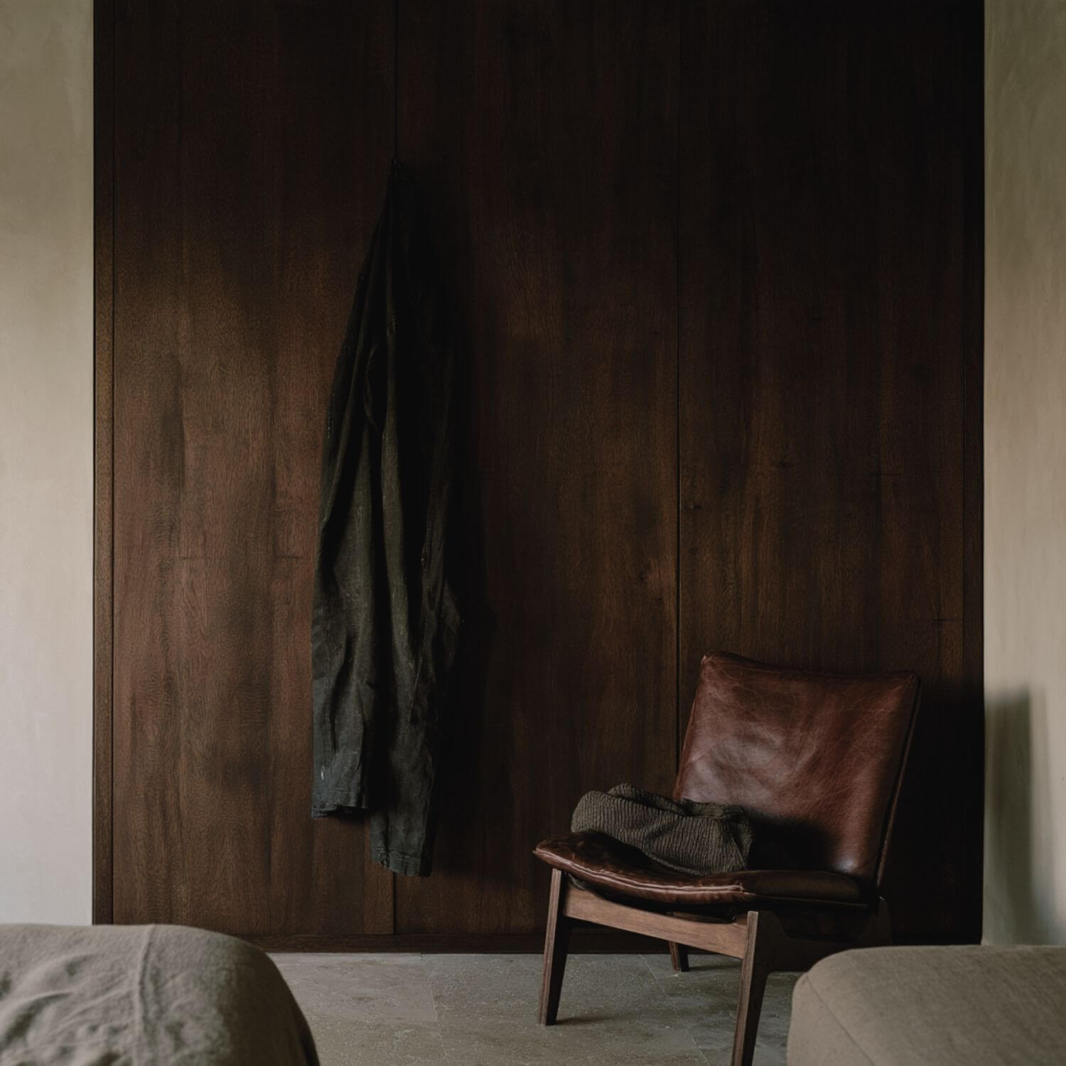 Silla de madera y cuero con ropa utilizada junto al armario de un dormitorio contemporáneo.